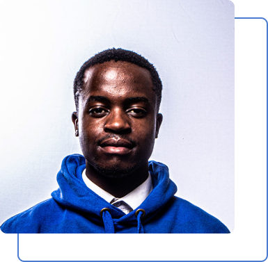 A handsome man wearing a blue jumper smiling infront of a white background.